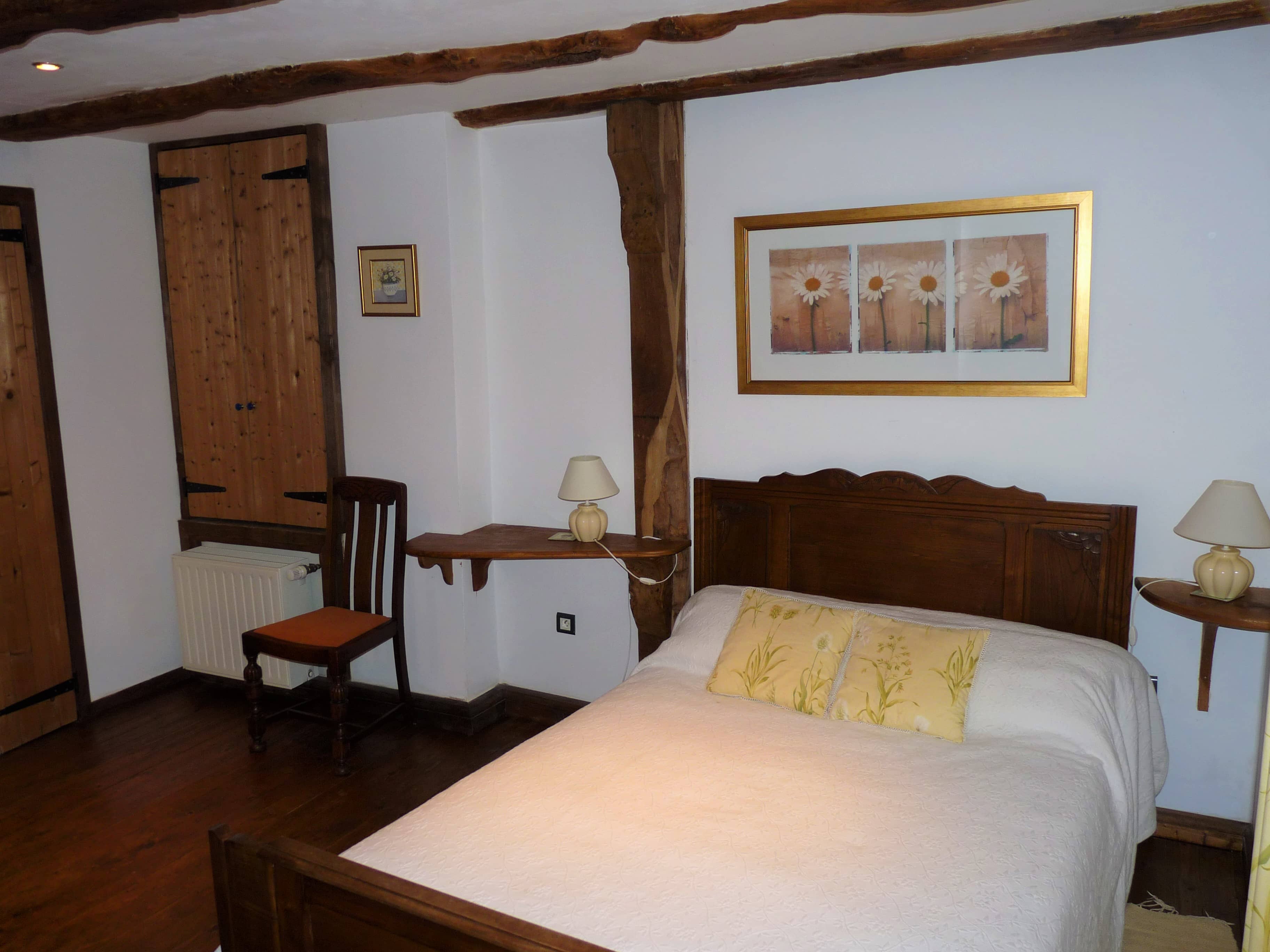 Spacious and comfortable bedroom of La Julerie cottage in Brittany, France, with a king-size bed, elegant rustic decor, a stone fireplace, and a panoramic view of the surrounding countryside. Perfect for a peaceful night's sleep after a day of sightseeing in the Brittany region.
